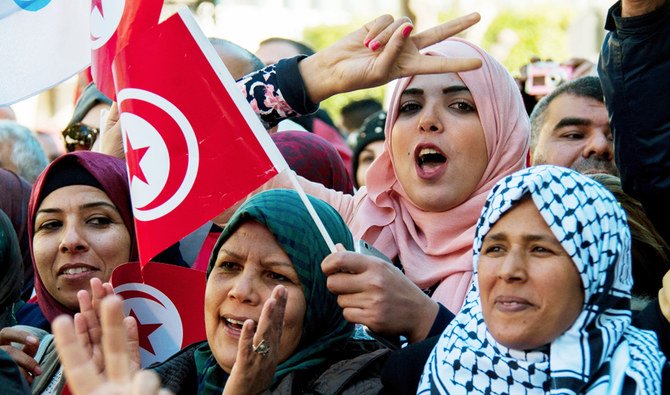 A Tunisian woman holds the national flag and make a sign during a rally in Tunis, Tunisia, Sunday, Jan. 14, 2018. (AP)