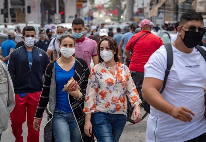 Moroccans wearing face masks walk along a street in the capital Rabat, after the authorities eased lockdown measures in some cities, put in place in order to limit the spread of the novel coronavirus, on June 25, 2020. (AFP/Fadel Senna)