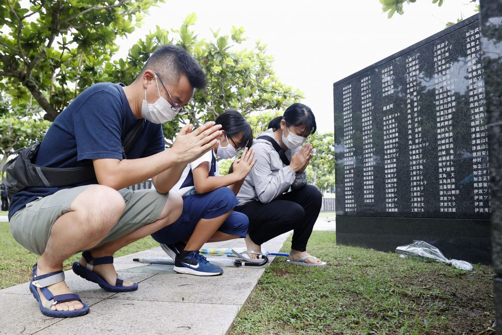People pray to commemorate the 75th anniversary of the end of the Battle of okinawa, in front of a 