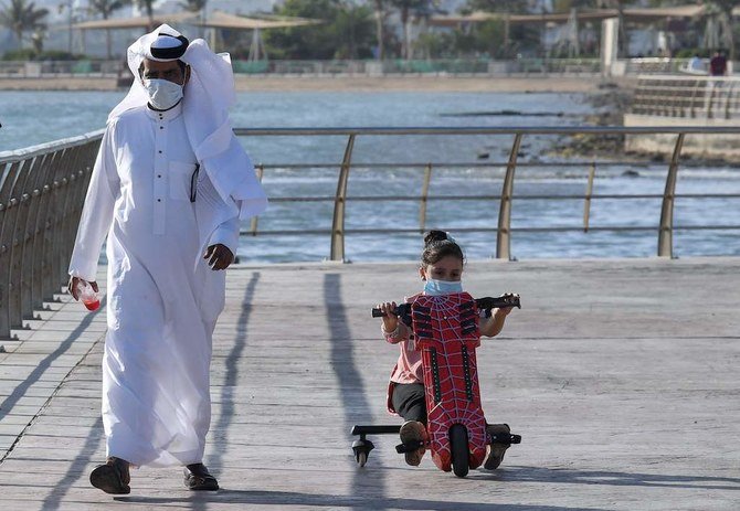 A Saudi man and his daughter stroll down the seafront promenade in the Saudi seaport of Jeddah, on June 21, 2020, as the country re-opens following the lifting of a lockdown due to the COVID-19 pandemic. (AFP)
