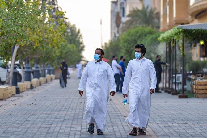 Mask-clad men walk along the promenade of Tahlia street in the centre of Saudi Arabia's capital Riyadh on June 21, 2020, as the country begins to re-open following the lifting of a lockdown due to the COVID-19 coronavirus pandemic. (AFP)