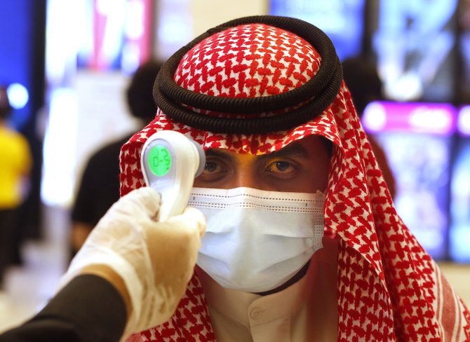 A Saudi cinema viewer has his temperature taken as he wears a face mask to help curb the spread of the coronavirus, at VOX Cinema hall in 