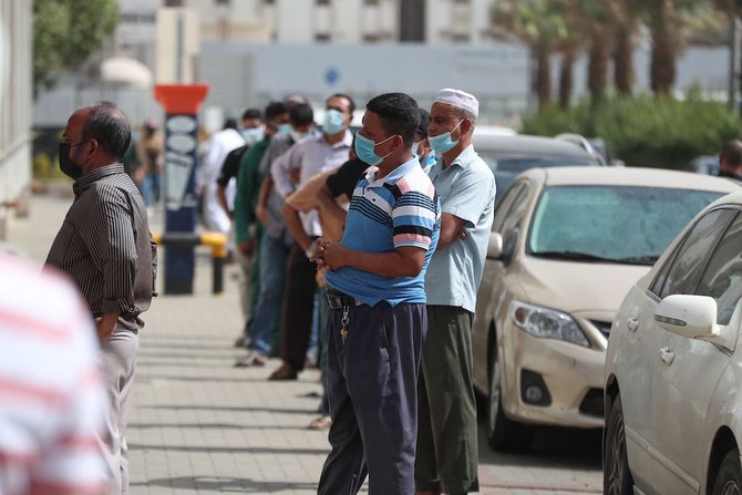 Mask-clad men wait outside a shop in Saudi Arabia's holy city of Mecca on May 31, 2020 as lockdown measures are eased amid the COVID-19 pandemic. (AFP)