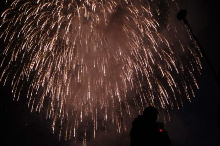 A journalist (right) films as fireworks explode near Tama river in Chofu in the western suburbs of Tokyo on June 1, 2020. (AFP)