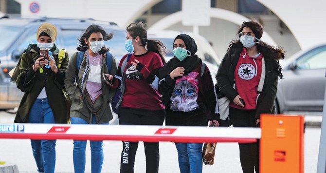 Young women wearing protective masks walk outside Beirut’s Rafik Hariri University Hospital, where a woman is treated for coronavirus. (AFP file photo)