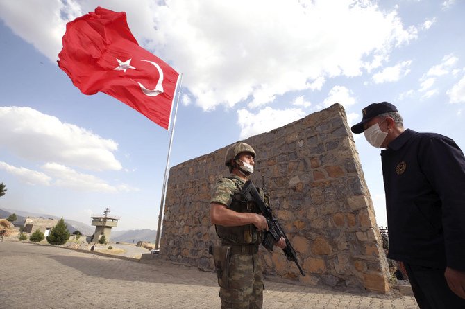 Turkish Defense Minister Hulusi Akar, wearing a face mask to protect against coronavirus, visits Turkish troops at the border with Iraq in Hakkari province on June 19, 2020. (Turkish Defense Ministry via AP, Pool)