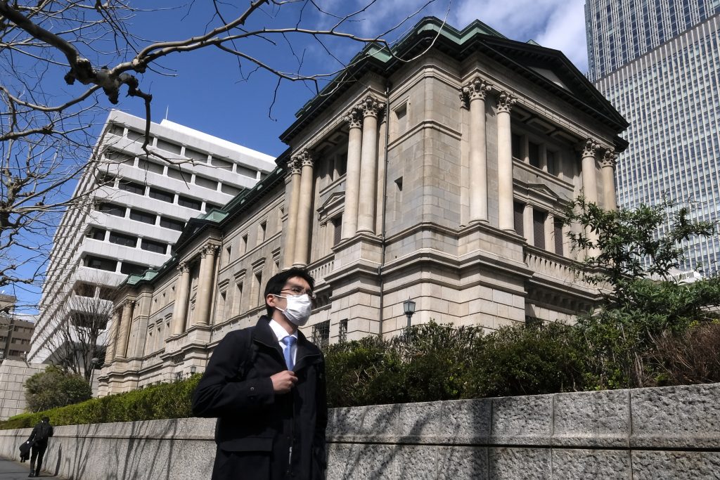 A pedestrian walks in front of the Bank of Japan headquarters in Tokyo on March. 16, 2020. (AFP)