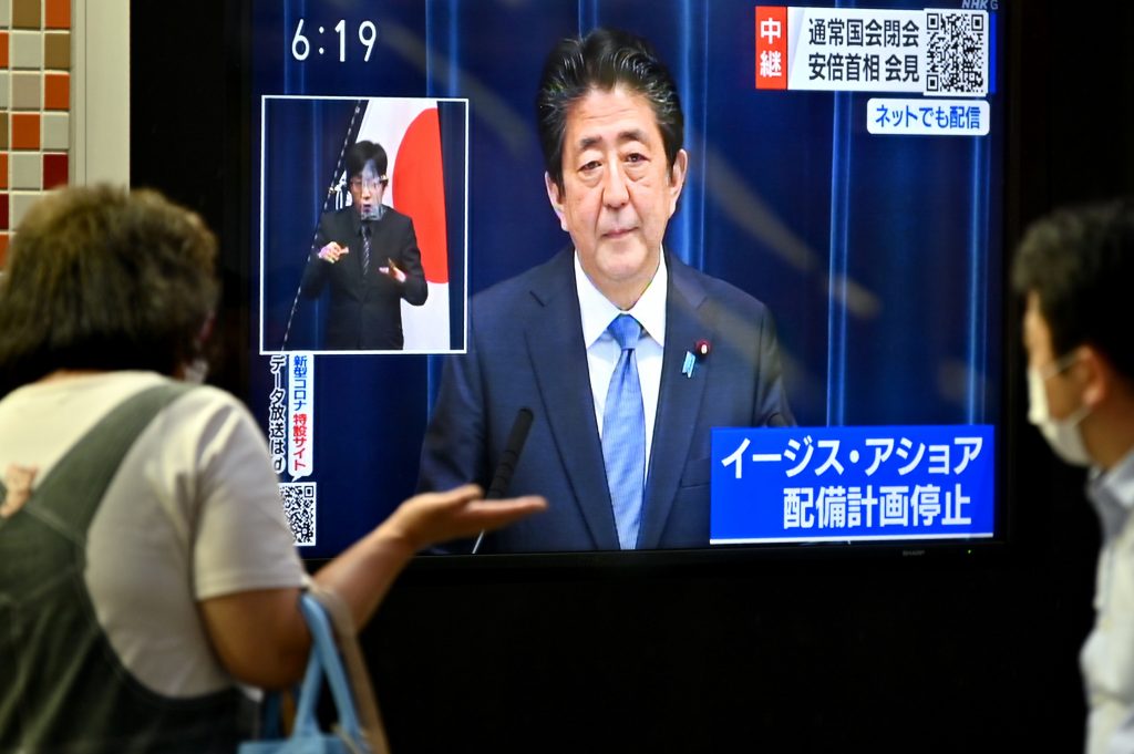 Pedestrians walk past as a television screen showing a broadcast of Japanese Prime Minister Shinzo Abe speaking during a press conference in Tokyo on June 18, 2020. (AFP)