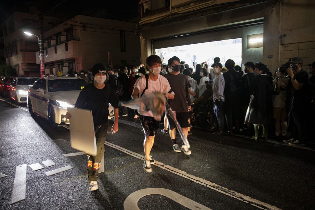 In this picture taken on July 9, 2020, two men hold artworks after taking them from Same gallery that organised a stealable art exhibition in Tokyo. (AFP)