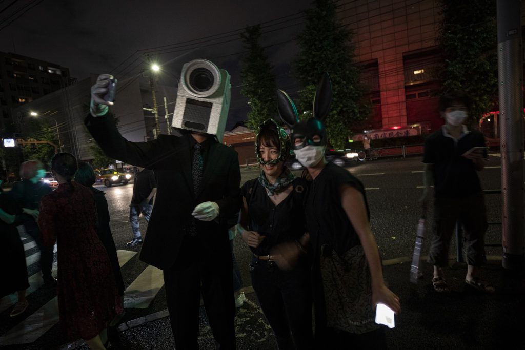 In this picture taken on early July 10, 2020, people wearing masks take a selfie outside Same gallery after the artworks of a stealable art exhibition were taken by visitors in Tokyo. (AFP)