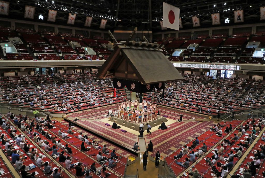 People sit apart to observe social distancing while watching wrestlers perform a ceremony ahead of their bouts during a new two-week sumo tournament at the Ryogoku Kokugikan, the main sumo arena in Tokyo, on July 19, 2020. (AFP)
