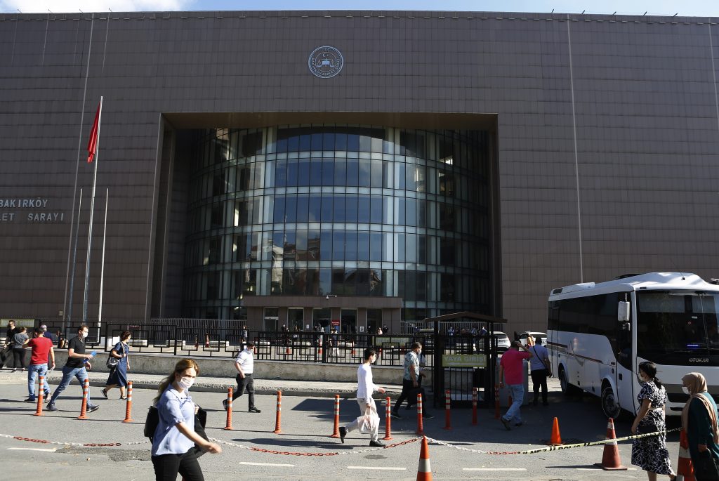 People walk outside a court in Istanbul, Friday, July 3, 2020, where the trial began for defendants accused of smuggling former Nissan Motor Co. chairman Carlos Ghosn out of Japan to Lebanon, via Turkey. A private airline official, four pilots and two flights attendants are on trial in Istanbul, accused of smuggling former Nissan Motor Co. chairman Carlos Ghosn out of Japan to Lebanon, via Turkey. Turkish prosecutors are seeking up to eight years in prison each for the four pilots and the airline official on charges of illegally smuggling a migrant, for helping Ghosn escape to Lebanon while he awaited trial in Japan. (AP Photo/Mehmet Guzel)