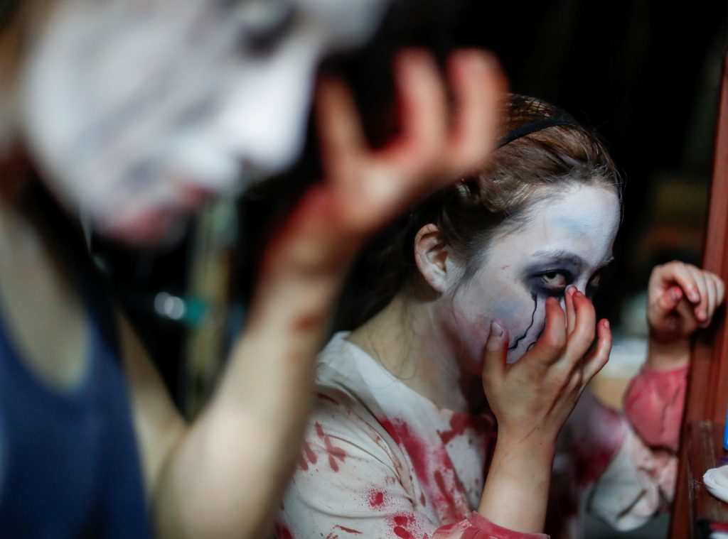 Actors dressed as zombies or ghouls put makeup on before a drive-in haunted house show, perfromed by Kowagarasetai (Scare Squad), for people inside a car in order to maintain social distancing amid the spread of the coronavirus disease (COVID-19), at a garage in Tokyo, Japan July 3, 2020. (Reuters)