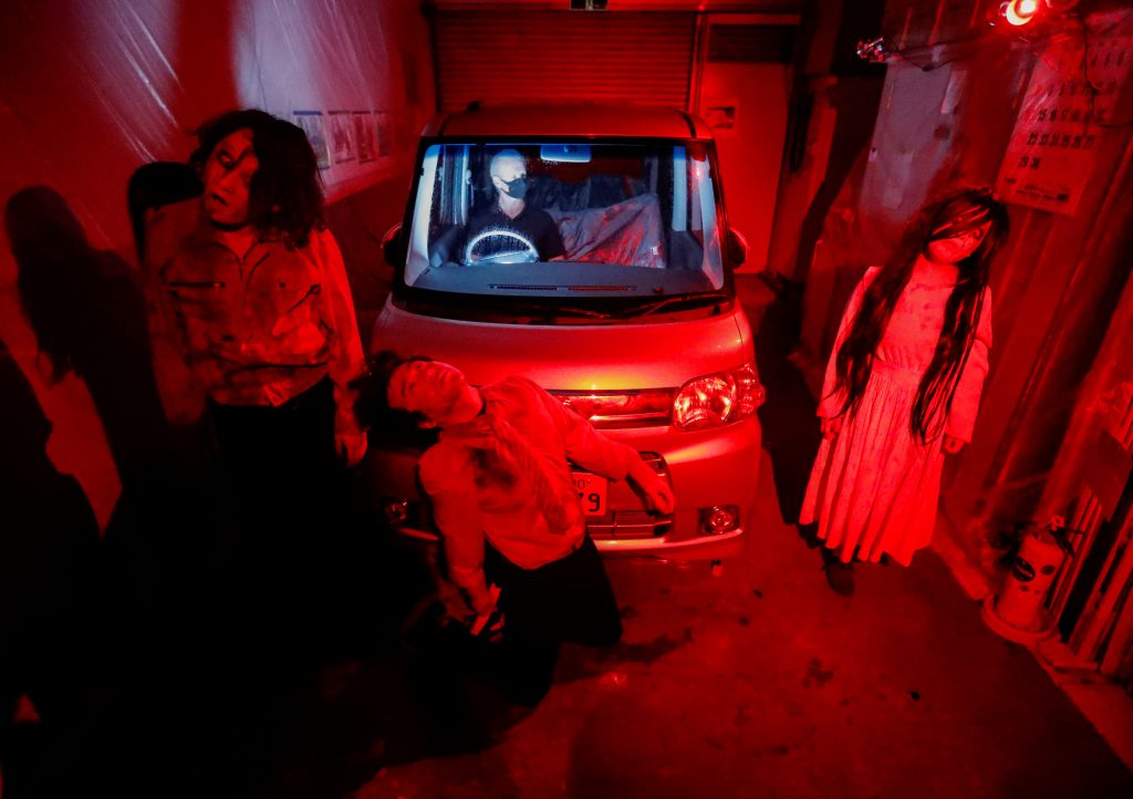 Actors dressed as zombies or ghouls perform during a drive-in haunted house show by Kowagarasetai (Scare Squad), for people inside a car in order to maintain social distancing amid the spread of the coronavirus disease (COVID-19), at a garage in Tokyo, Japan July 3, 2020. (Reuters)
