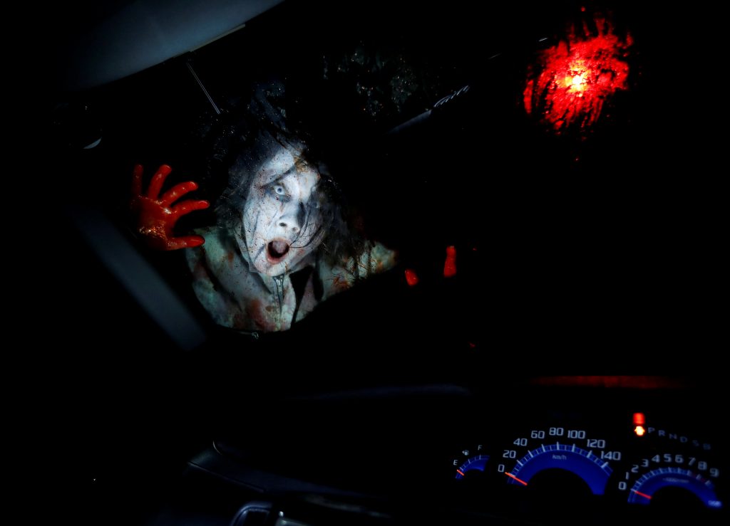 An actor dressed as a zombie performs during a drive-in haunted house show, performed by Kowagarasetai (Scare Squad), for people inside a car in order to maintain social distancing amid the spread of the coronavirus disease (COVID-19), at a garage in Tokyo, Japan July 3, 2020. (Reuters)