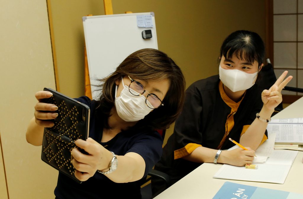 Jiho Yoshimizu takes a selfie with a Vietnamese migrant worker who lost her job amid the coronavirus disease (COVID-19) outbreak, while she helps the migrant worker studying Japanese language at a Buddhist temple which has turned into a shelter for young Vietnamese migrant workers in Tokyo, Japan, July. 2, 2020. (File photo/Reuters)