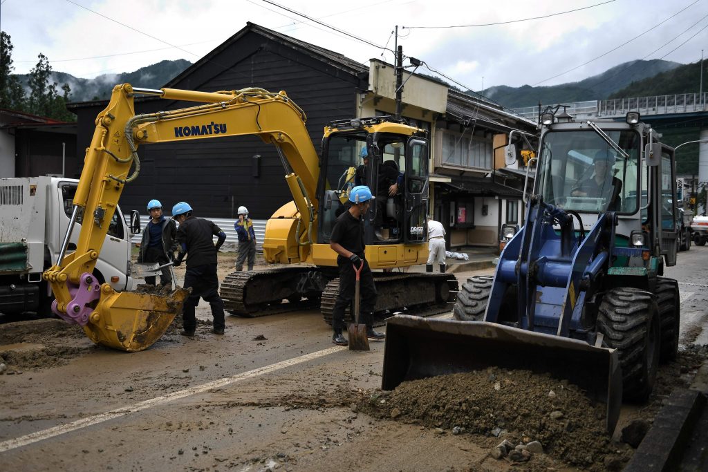 Workers clear debris and mud outside homes following heavy rains and flooding in the village of Gero, Gifu prefecture on July 9, 2020. Japanese emergency services and troops were scrambling to reach thousands of homes cut off by devastating flooding and landslides that have killed dozens and caused widespread damage. (AFP)