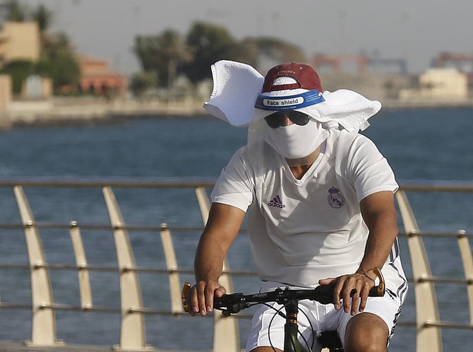 A vacationer rides his bicycle while wearing a face shield and mask to help prevent the spread of the coronavirus, at the Red Sea beach in Jeddah, Saudi Arabia. (File/AP)