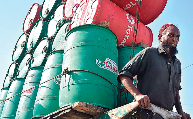 An Indian laborer pulls a cart laden with empty oil drums. OPEC and its allies led by Russia have cut output by 10 million bpd since May. (AFP)