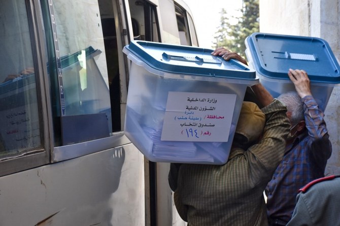 Syrian men carry ballot boxes onto a bus to hand them over to the police. (AFP)