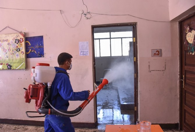 A Syrian worker disinfects a classroom at a school which will be used as a polling station in the northern city of Aleppo. (AFP)