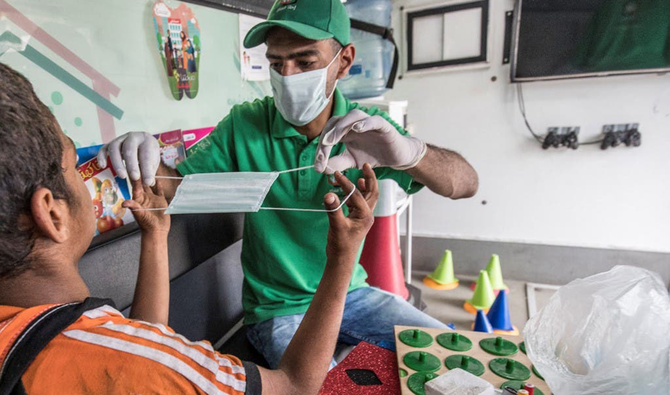 A social worker shows a homeless child the proper way to use a face mask inside one of the mobile units run by the Egyptian authorities in Cairo’s Abbasia district. (AFP)