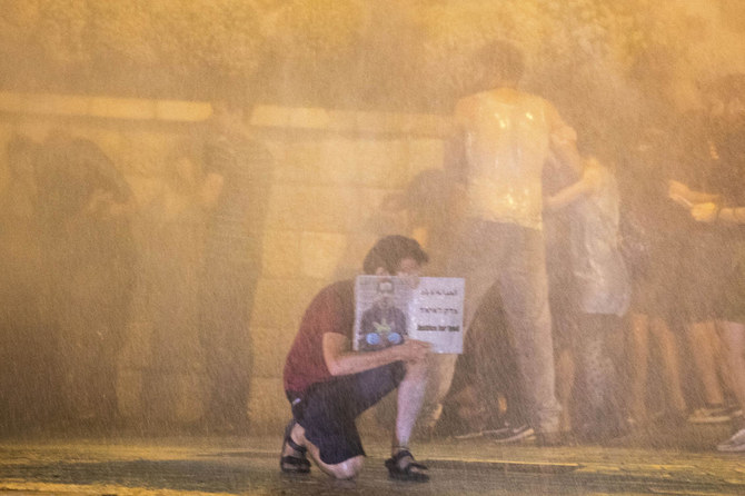 Police use a water cannon to disperse demonstrators as one holds a banner reading “Justice to Eyad Hallaq,” a Palestinian with severe autism that was killed recently by Israeli border police, during a protest on Friday, July 24, 2020. (AP)