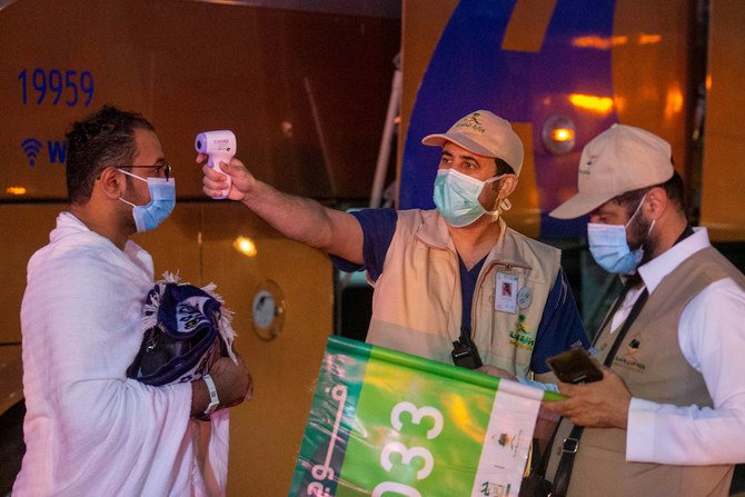 A health worker checks the temperature of a Muslim pilgrim heading to the Meeqaat to hold the intention of the Haj pilgrimage amid the coronavirus disease (COVID-19) pandemic, in Makkah July 29, 2020. (Reuters)