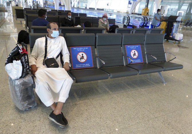 A passenger sits beside posters displaying social distancing restrictions as he waits for his flight at the King Abdulaziz International Airport in Jeddah, Saudi Arabia, on Tuesday July 28, 2020. (AP)