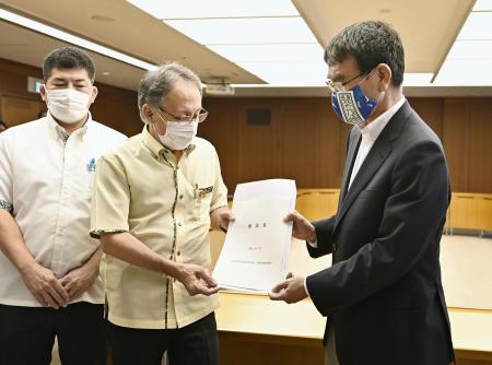 Okinawa Gov. Denny Tamaki (center) and Japanese Defense Minister Taro Kono (right) hold Okinawa's request document during their meeting at the Defense Ministry in Tokyo, Wednesday, July 15, 2020. (Kyodo News via AP)