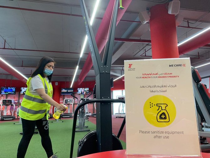 A woman, wearing a protective face mask, sanitises a machine before a training session at a gym in Saudi Arabia’s capital Riyadh. (File/AFP)