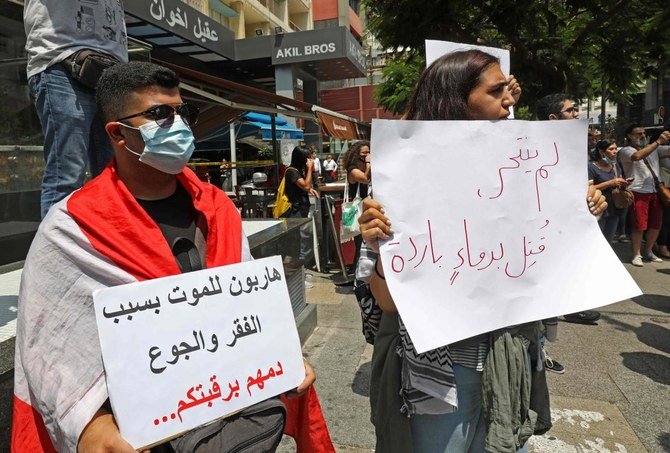 A demonstrator carries a placard (R) which reads in Arabic “He did not commit suicide, he was killed in cold blood” as they gather to denounce the death of a man who committed suicide in Beirut on July 3, 2020. (AFP)