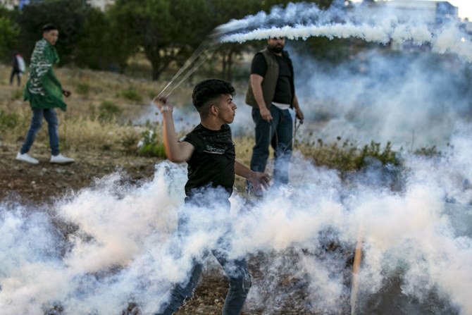 Palestinians use slingshots to throw back tear gas canisters at Israeli forces during clashes following a demonstration against Israel’s plan to annex parts of the West Bank, Ramallah, July 1, 2020. (AFP)