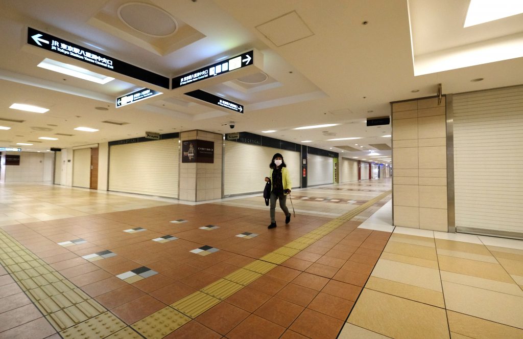 A woman walks in an underground shopping mall with closed shops, near a Tokyo railway station. April. 8, 2020. (AFP)