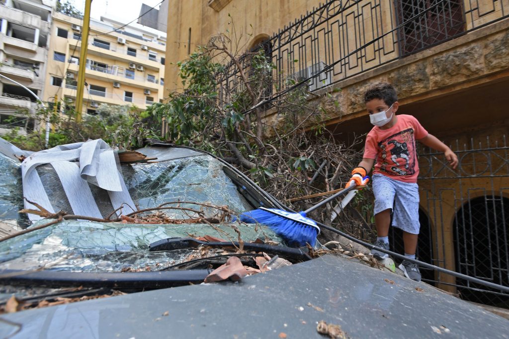 A Lebanese boy cleans a damaged car in Beirut on August 11, 2020, after a huge chemical explosion devastated large swathes of the capital. (AFP)