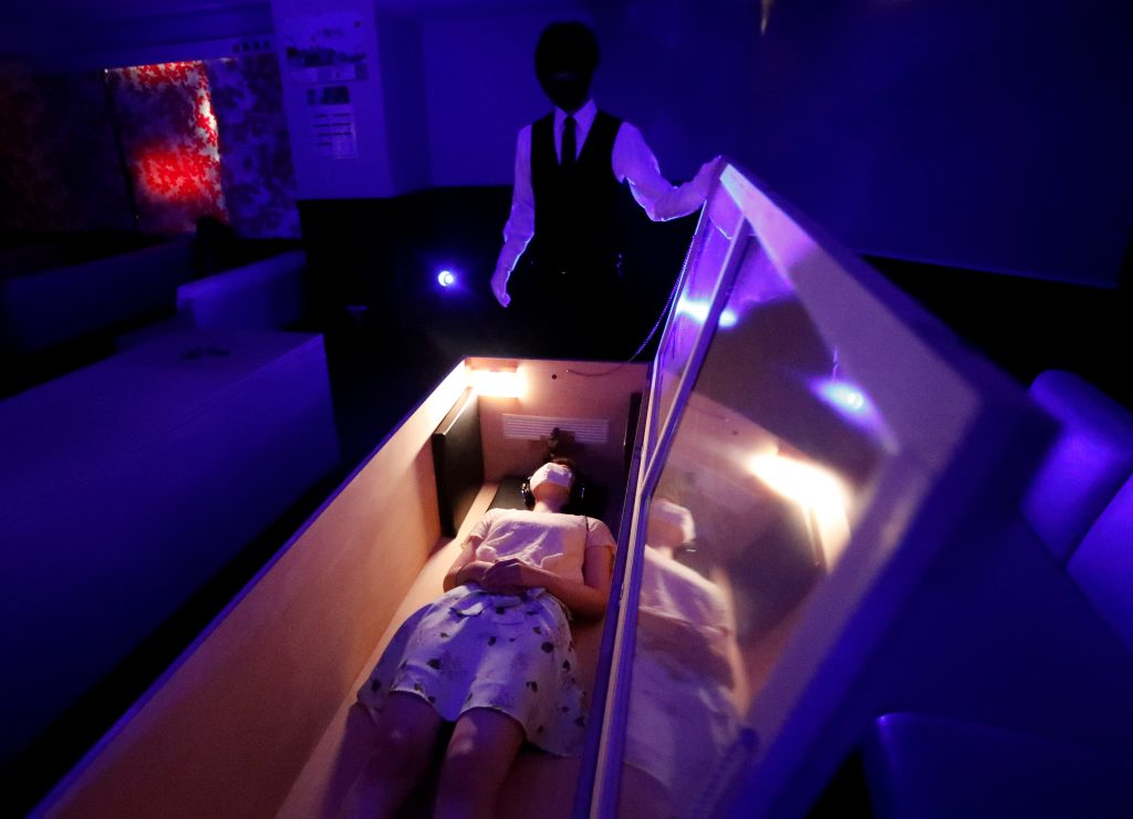 A participant lies inside a mock of coffin with plastic shields to maintain social distancing amid the spread of the coronavirus disease (COVID-19), during a coffin horror show, in Tokyo. (Reuters)