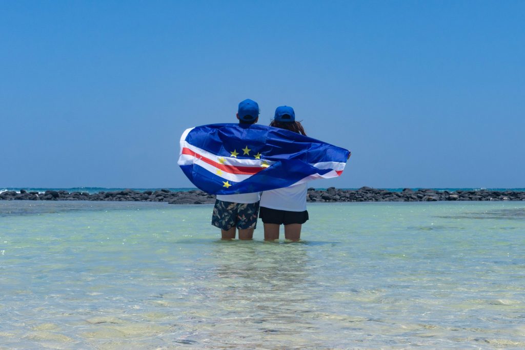 Japanese couple Rikiya (R) and Ayumi Kataoka (L) posing with the official Olympic Cape Verde uniform and national flag as a gift from the National Olympic Committee in Santa Maria in Cape Verde. (instagram/rikiya_trip) 