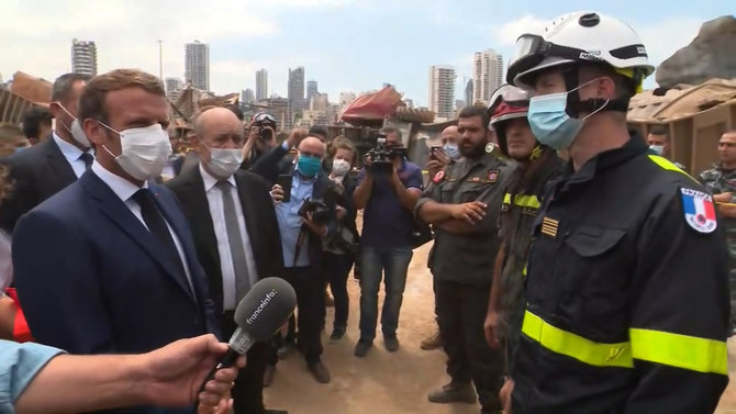 A video grab shows French President Emmmanuel Macron (L) speaking with a member of a French rescue team which arrived overnight to support relief efforts at the port of Lebanon's capital Beirut on August 6, 2020y. (POOL / AFP)