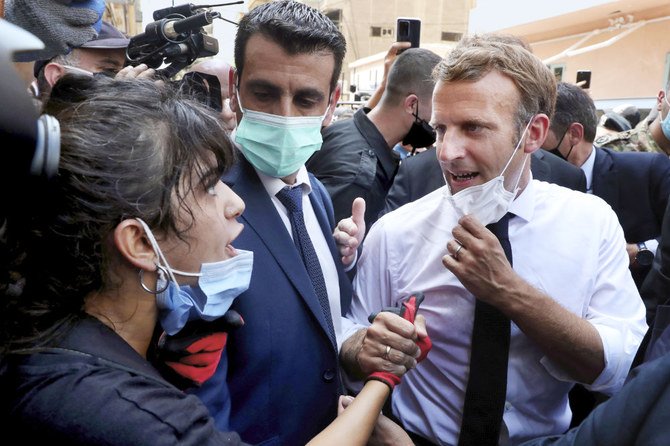 French President Emmanuel Macron speaks to the woman who asked him for help during his visit to Beirut’s devastated Gemmayzeh neighborhood. (AP)