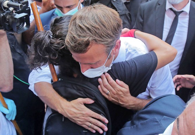 French President Emmanuel Macron hugs a woman during his visit to Beirut’s devastated Gemmayzeh neighborhood. (AFP)