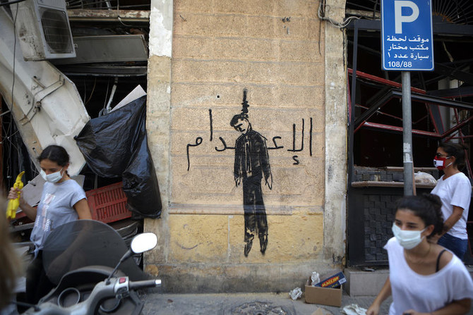 Members of the Lebanese civil society carrying brooms used for clearing debris, walk past a wall painting depicting a hanged politician and reading (death sentence in Arabic) in the partially damaged Beirut neighbourhood of Mar Mikhael on August 7, 2020. (AFP)