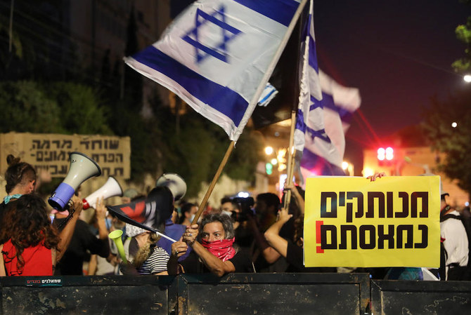 Israeli protesters wave national flags and chant slogans against the government near the prime minister's residence in Jerusalem on August 6, 2020. (AFP)