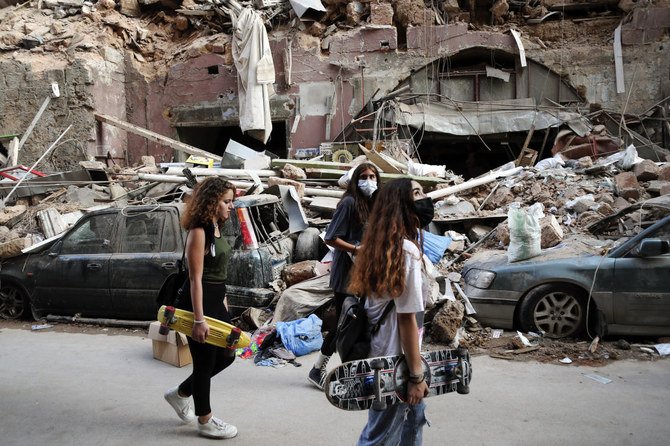 Women walk past destroyed cars at a neighborhood near the scene of Tuesday's explosion that hit the seaport of Beirut, Lebanon, Friday, Aug. 7, 2020. (AP)