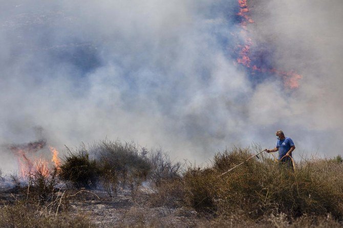 An Israeli worker from the Nature and Parks Authority attempts to extinguish a fire caused by a incendiary balloon launched by Palestinians from the Gaza Strip, on the Israeli side of the border between Israel and Gaza on August 12, 2020. (AP)