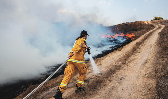 An Israeli firefighter extinguishes a fire caused by an incendiary balloon from Gaza, on the Israeli side of the border between Israel and Gaza. (AP)