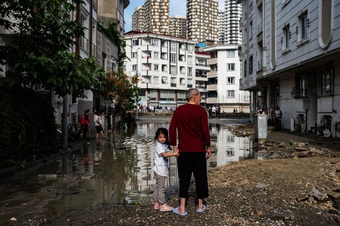 A man and a child stand in a flooded street on June 23, 2020 in the Esenyurt district of Istanbul where at least one person died as heavy rains and hail storms lashed Istanbul today. (File/AFP)