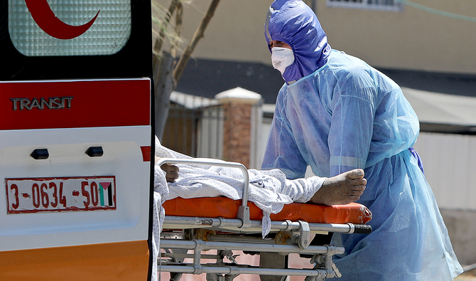 A Palestinian health worker wearing protective clothing loads into an ambulance a stretcher carrying the body of a 61-year-old man who died after contracting the coronavirus disease (COVID-19), in the northern Gaza Strip August 26, 2020. (Reuters)
