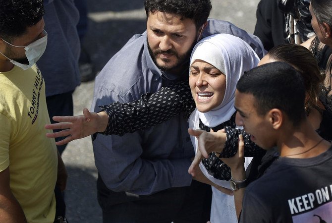 The wife of Rami Kaaki, one of ten firefighters who were killed during the last week's explosion that hit the seaport of Beirut, tries to reach her husband's coffin during his funeral, at the firefighter headquarters in Beirut on Tuesday. (AP)