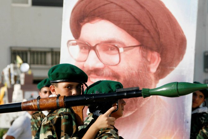 A Hezbollah member carries a mock rocket next to a poster of the group's leader Sayyed Hassan Nasrallah in Sidon, southern Lebanon. (REUTERS/Ali Hashisho/File Photo)