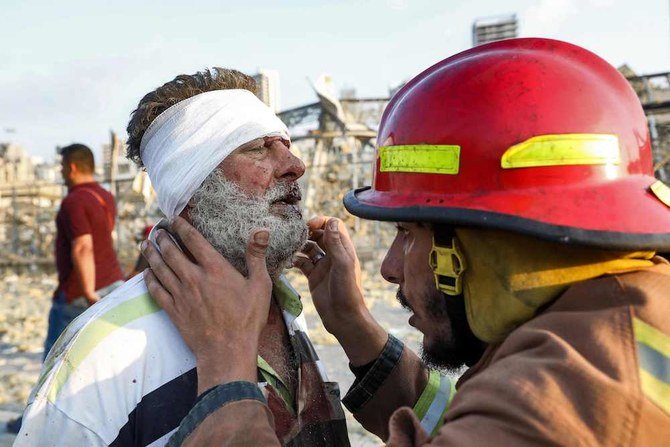 A wounded man is checked by a fireman near the scene of an explosion in Beirut on Aug. 4, 2020. (AFP)